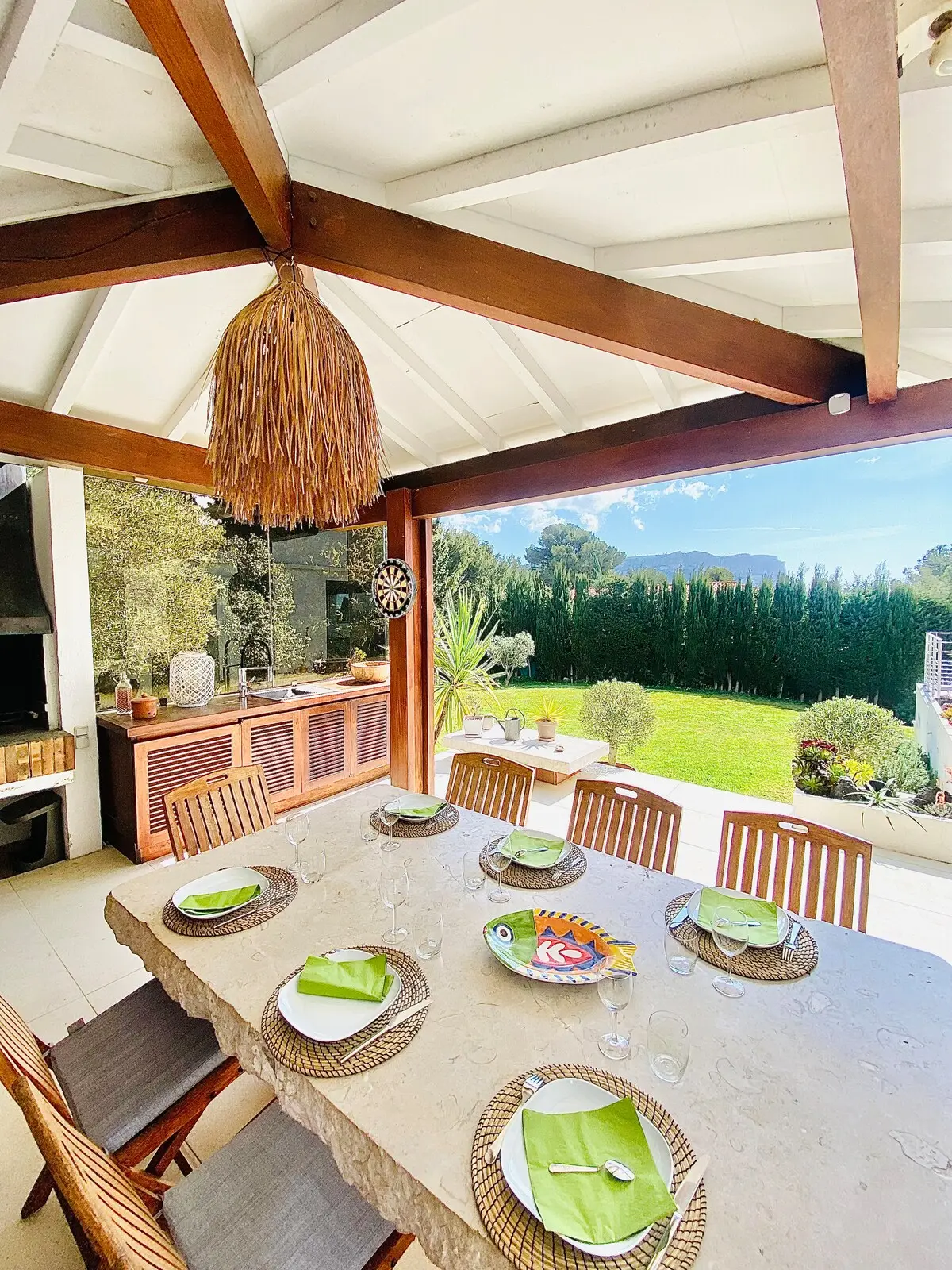 Table dressée sous la cuisine d’été couverte, ouverte sur le jardin