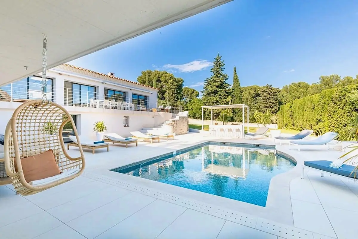 Fauteuil suspendu en osier face au bassin et à la villa