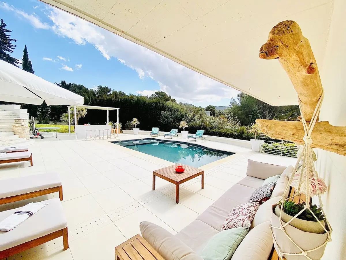 Salon d’extérieur en bord de piscine, à l’ombre du parasol