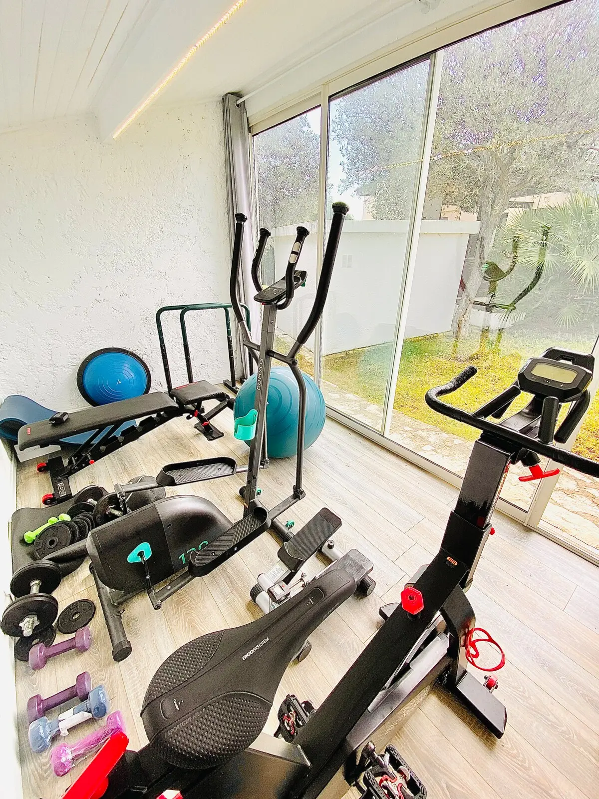Salle de sport vitrée, vélo elliptique, poids et tapis
