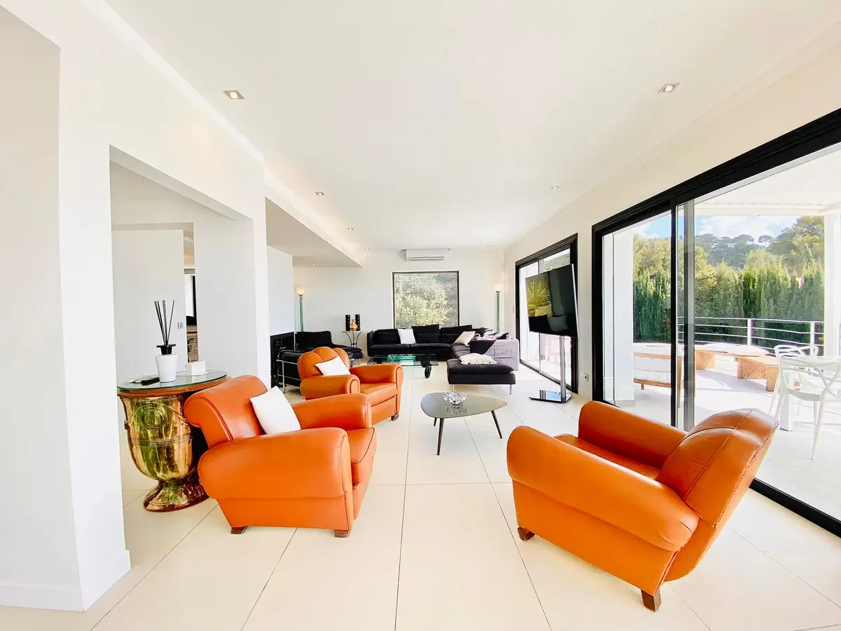 Fauteuils club orange et grande baie ouverte sur la terrasse