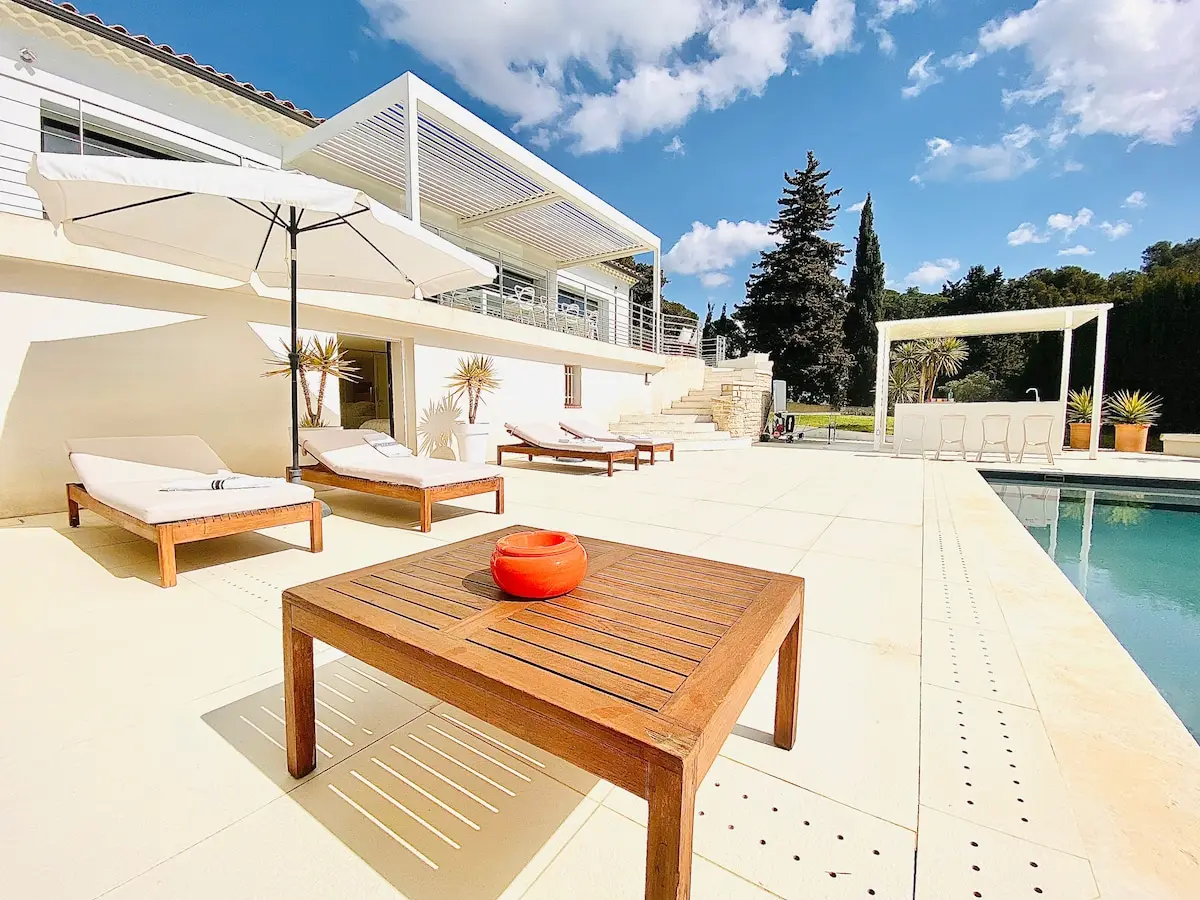 Terrasse en pierre claire, transats et table en teck